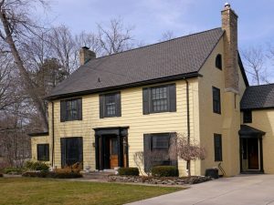Two-storey country house with yellow aluminum siding and black accents
